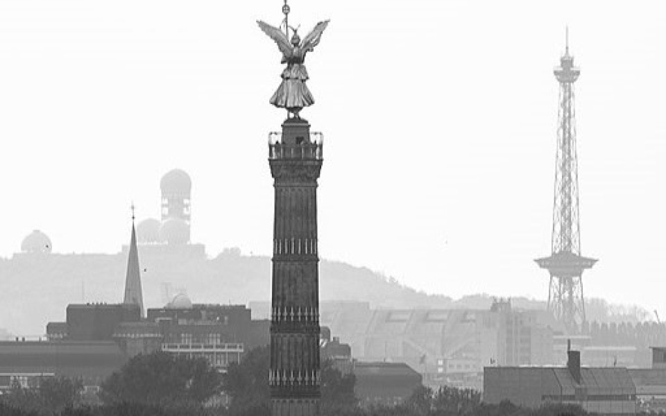 A black & white image of the angel atop the Victory Column in Berlin with the city's skyline in the background.