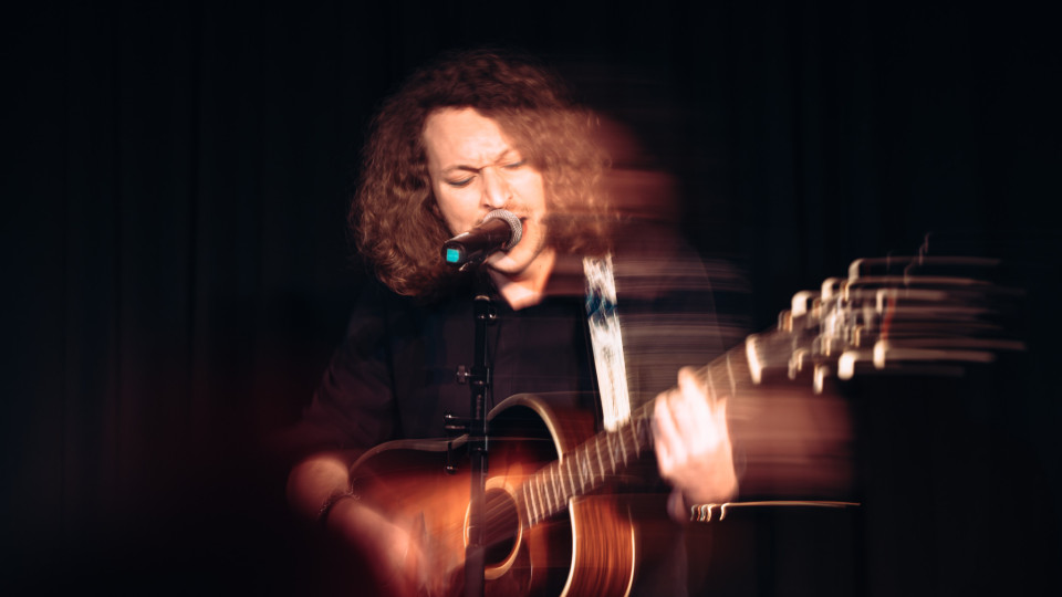 A picture of a performer with a microphone and a guitar.