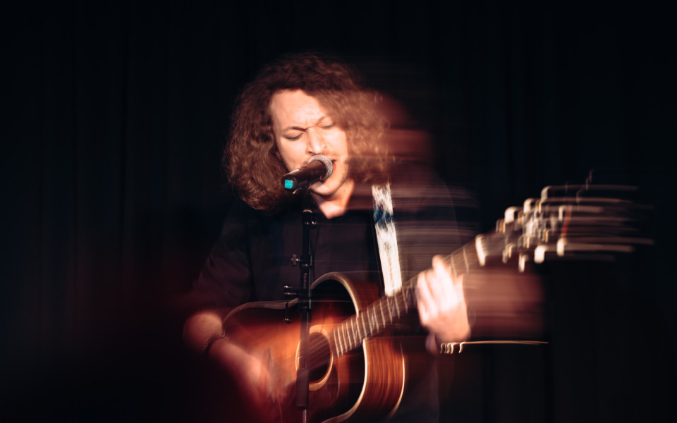 A picture of a performer with a microphone and a guitar.