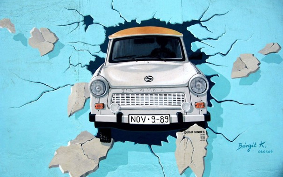 A paining of a Trabant auto breaking through a blue wall.