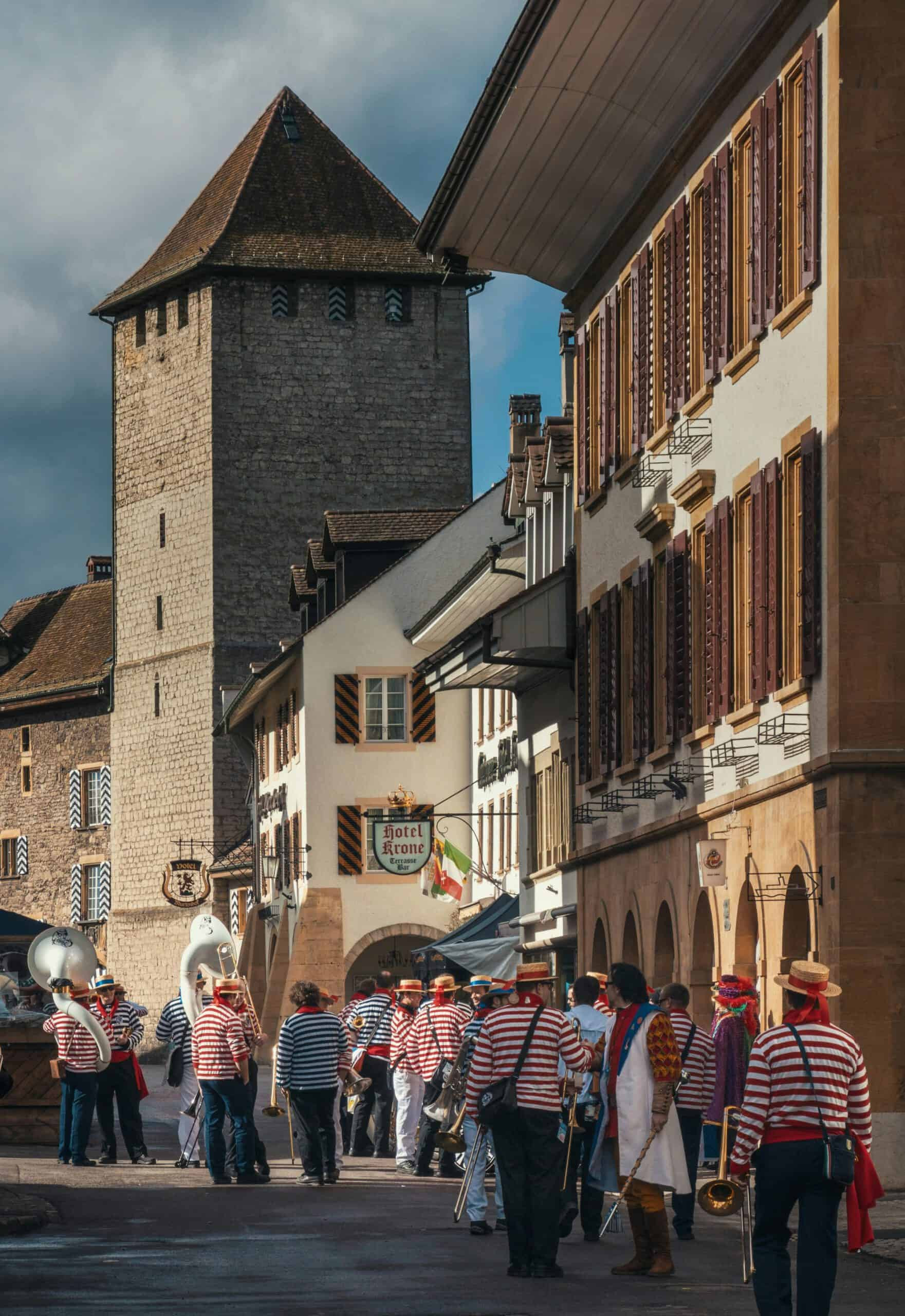 A brass band gathers on a street in preparation of a Carnival performance.