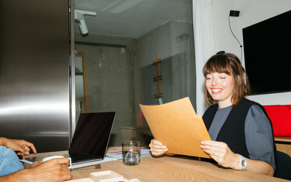 Woman reading something on a paper, sat at the desk.